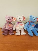 First image showing purple variegated, pastel confetti, and blue U.S. flag bears with Ty tags
