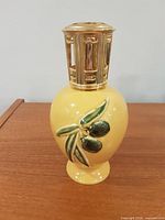 Full view of yellow ceramic Lampe Berger lamp with gold vented crown and olive motif