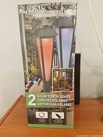 Retail box front showing Paradise 2 solar torch lights with remote