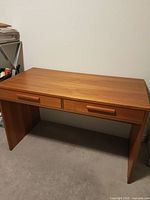 Front view of teak desk showing drawers and panel legs