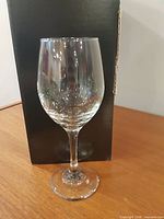 Single clear wine glass standing in front of packaging