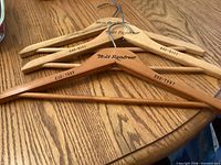 Three Holt Renfrew wooden hangers on table