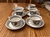 Set of 5 teacups and 6 saucers arranged on table