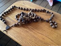Full length view of oversized wooden rosary laid out on table
