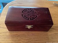 Closed rosewood jewelry box showing longevity cut-out and brass clasp