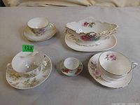 All items arranged: four teacup/saucer sets, floral gravy boat, oval tray