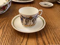 Cup on saucer showing portraits, crests, border and condition