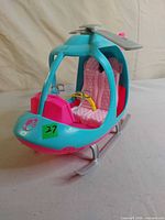 Front and side view showing Barbie logo, two pink seats and grey landing skids