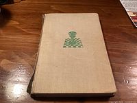 Front cover of beige cloth hardcover book with green chess emblem