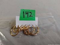 All three pairs of gold tone hoop earrings on backing card