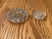 Two glass flower frogs on wooden surface, showing size comparison