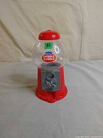 Front view of red Dubble Bubble gumball dispenser showing logo and coin mechanism