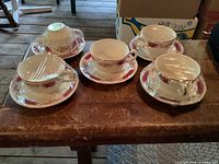 Set of five teacup and saucer pairs on table
