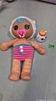 Full view of Lalaloopsy-style doll lying flat with bottle accessory beside it