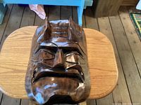 Front view of carved wood mask showing facial details and horns