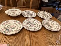 Overview of five dinner plates and vegetable bowl on table