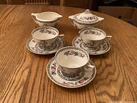 Full set on table showing three cups, three saucers, creamer and covered sugar bowl