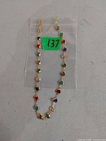 Full view of goldtone necklace laid flat, showing heart-shaped multicolor stone links