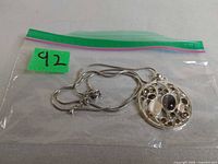 Full view of necklace inside plastic bag showing chain and pendant front