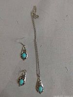 Full view of necklace and both earrings laid flat