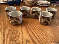 Six owl motif stoneware cups on wooden table