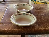 Two oval dishes on table, top view shows shape and crest placement