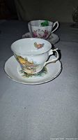 Front view of both teacups and saucers showing patterns and gold trim