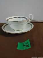 Side view of teacup on saucer showing floral border and gold trim