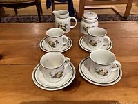 Overall view: 4 cups with saucers, creamer, sugar bowl on table
