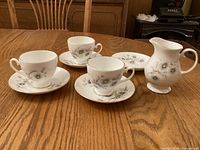 Three teacups on saucers with creamer displayed on table