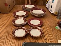 Stacked burgundy and gold edge plates and bowls on table