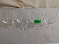 Set of four small etched glass brandy snifters on flat surface