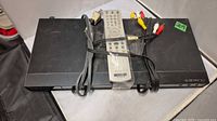 DVD player with remote, RCA cables and power cord bundled on top