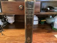 Spine view of hardcover book showing title, author, volume number, publisher emblem; wear visible