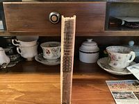 Spine view showing title and publisher on shelf with teacups