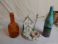 Front view showing amber bottle, ceramic house candle holder and painted bottle