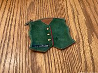 Front of green suede vest-shaped coin purse showing buttons, Innsbruck embroidery, red trim, and zipper