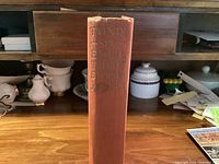 Spine view showing red cloth cover and gilt title lettering