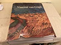 Front cover of Vincent van Gogh hardcover with Wheatfield artwork, visible tear on dust jacket