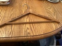 Full view of wooden coat hanger showing brand stamping and hook