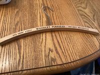 Front of wooden hanger showing Woodley Furriers address and phone