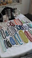 Full table view of all necklaces laid out and others on display stand