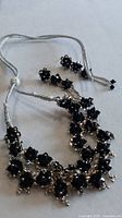 full view of silver-tone necklace with black bead clusters