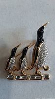 Front view of brooch showing three penguins with crystals and enamel