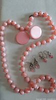 Full view of pink bead necklace arranged with three earring pairs