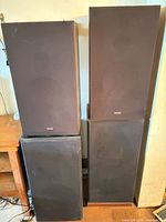 Front view of all four floor speakers showing size, color, brand badges, and condition.