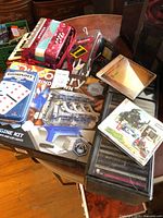Grouped lot showing accordion, engine kit box, dominoes tin, CD wallet, loose CDs