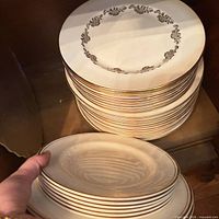 Stack of plates with gold trim and small oval platter