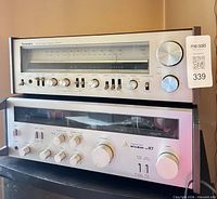 Front view of stacked Technics and Mitsubishi receivers showing controls and model markings