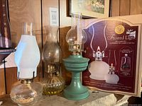Three assembled oil lamps and boxed set on shelf